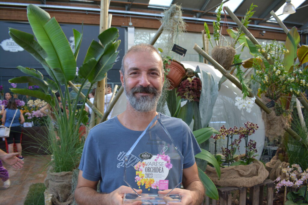 Giulio Farinelli di Il Sughereto con alle spalle la Migliore Orchidea della mostra Varese Orchidea 2023: il Bulbophyllum phalaenopsis. Foto di Francesca Castiglione e coltivazione di Il Sughereto